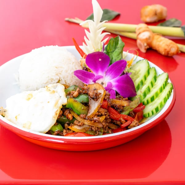 Thai basil stir-fry with minced meat, bell peppers, fried egg, rice, and cucumber slices.